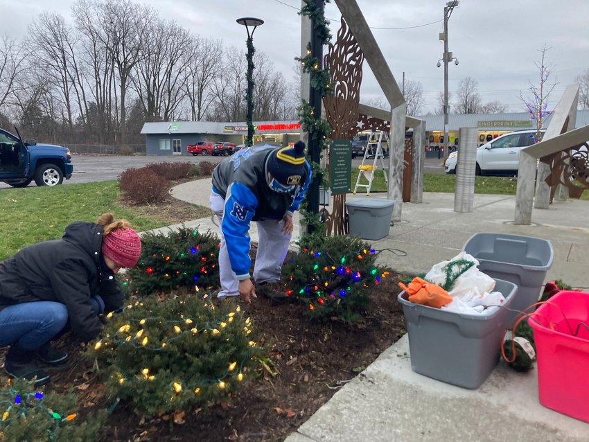 Volunteers add holiday lights to bushes in the Plaza at Pleasant Grove Rd. and Holmes Rd. in preparation for Friday's holiday event. 