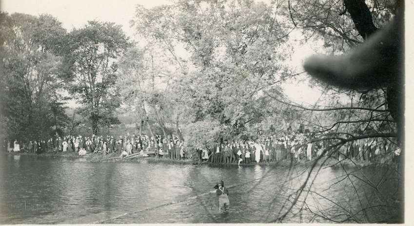 A real photo postcard from about 1920. A photographer wades in a pond, assembling a group for a panoramic photo.