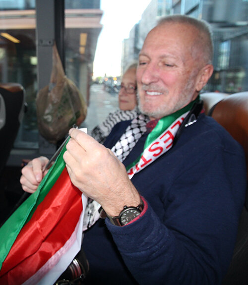 John Polany, 71, holds a Palestinian flag as he prepares to deboard the bus in Washington.