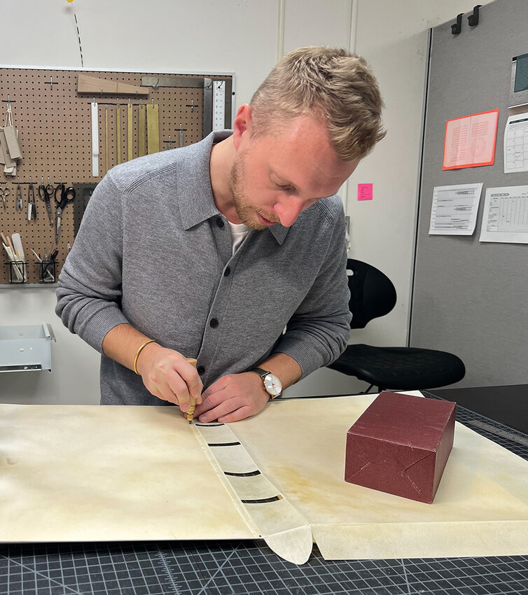 Garrett Sumner prepares the parchment cover for “Geographia.”