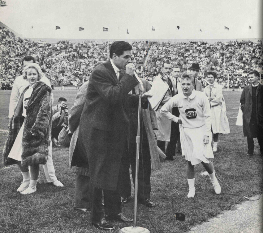 Cheerleader Sue Mills in a photo of a 1959 Spartan football game. Actor John Gavin leads the crowd in scripted chants for the soundtrack of the movie “Spartacus.”