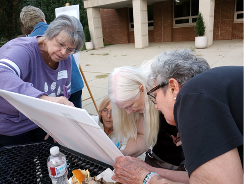 Diane Sanderson, Jill Campbell-Mason, Nanette Mathe and Jules Vander Galien work together on an art piece at a guild picnic at the Neighborhood Empowerment Center.