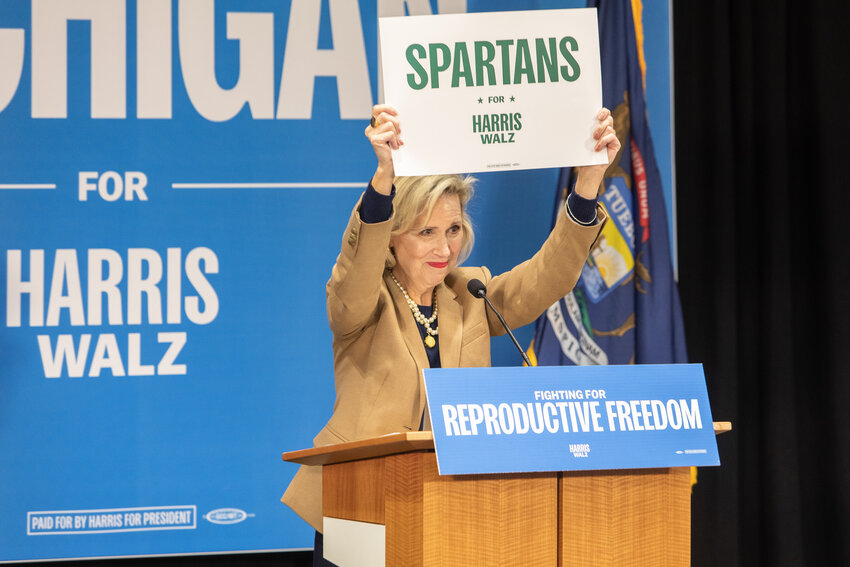 Gwen Walz holds up a "Spartans for Harris-Walz" sign during her stop at Lansing Community College's West Campus.