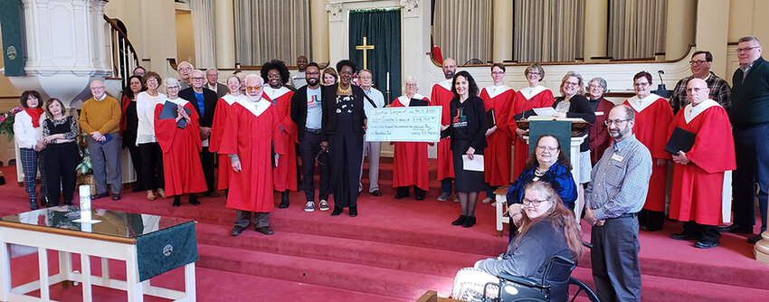 Courtesy photo
Congregants gathered at Lansing First Presbyterian Church to present the first installment of a $100,000 pledge to the Justice League Feb. 4, 2024. Bryan, in black, is standing left of the check.