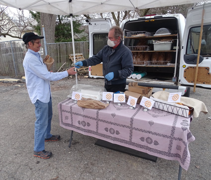 A customer picks up baked goods from vendor Kevin Cosgrove of Stone Circle Bakehous at the April 1 Allen Farmers&rsquo; Market. The market is resuming operations April 22 after a two-week hiatus.