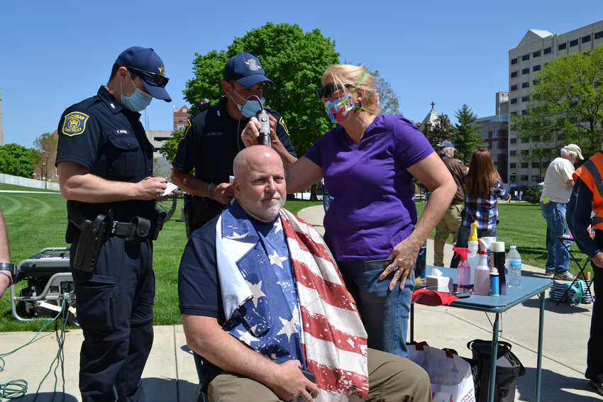 A man receives a haircut while police officers look on. They were not distributing tickets.
