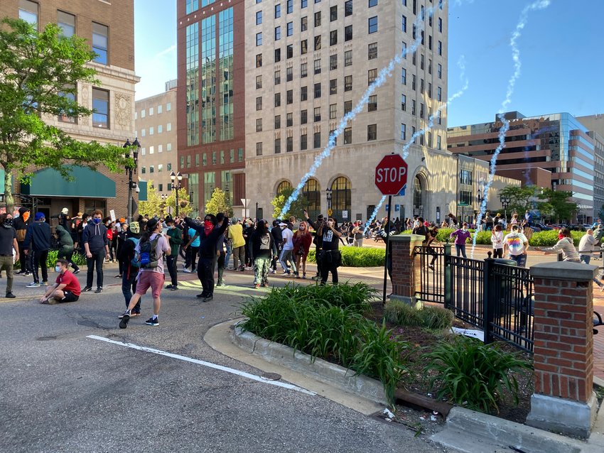 Tear gas canisters landing among protesters in downtown Lansing as police in riot gear begin their effort to disburse protesters after some set a car on fire.