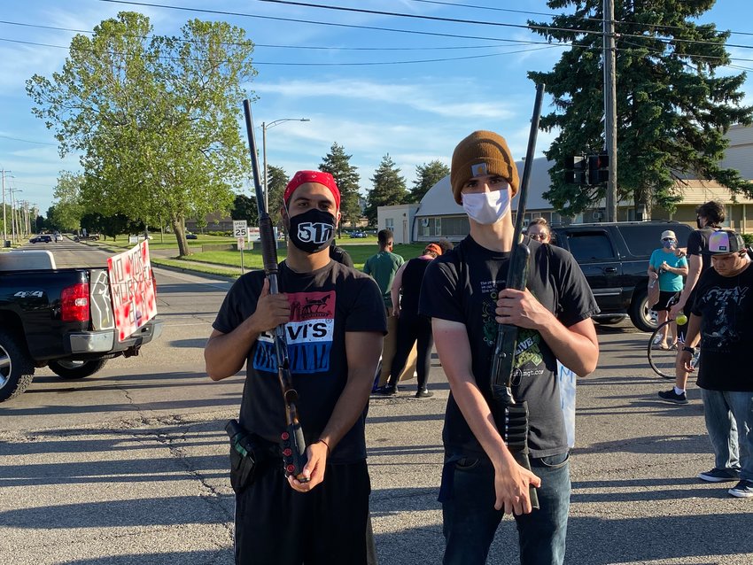 Two protesters pose as marchers reach the intersection of Marshall and Saginaw streets on their way to Frandor. The two said they have open carry licenses for the shotguns in their arms. They identified themselves as (right) James Bobier, who said he moved here from Virginia three years ago, and Alex Felipe Balderas of Lansing.