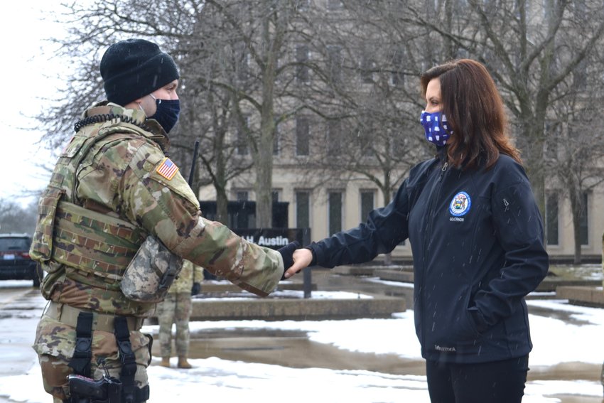 Gov. Gretchen Whitmer shakes hands with a member of the National Guard.