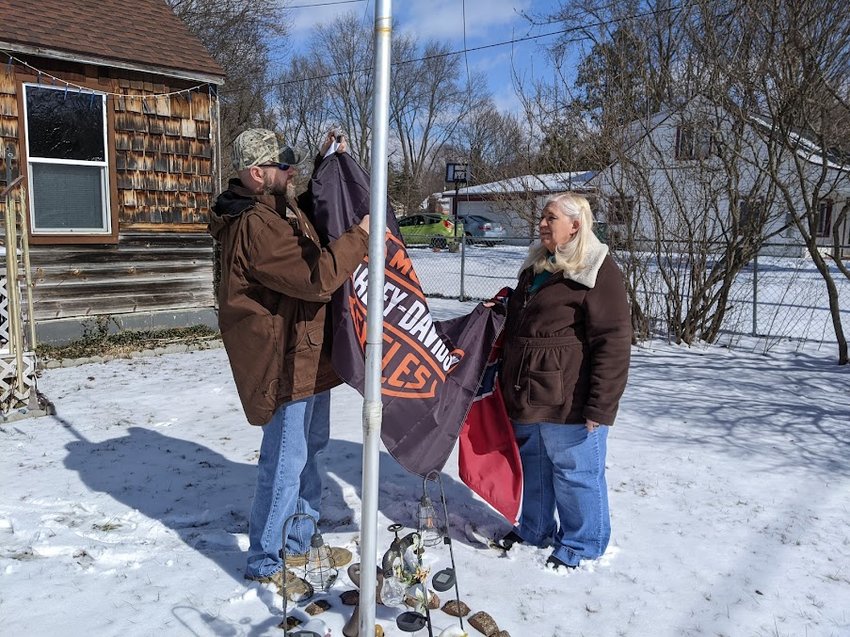 Sue Chapman and her son Kirk swap out a Confederate flag for a Harley Davidson one at Sue Chapman&rsquo;s southeast Lansing home.