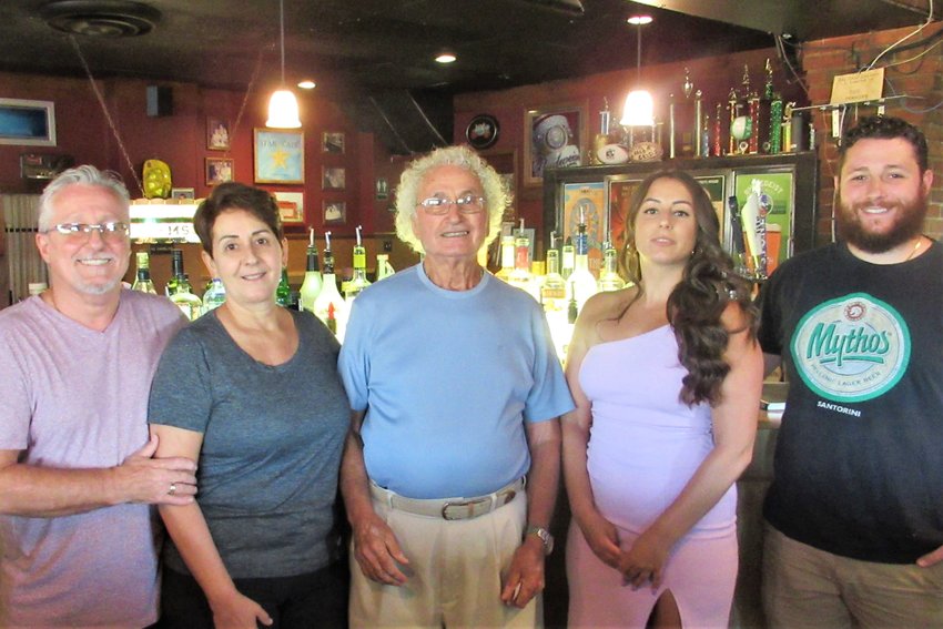 Three generations pose behind the bar at Harry&rsquo;s Place. (From left) Hugh and Harea Bates, current owners; previous owner Art Arvanites, Harea Bates&rsquo; father; Kristi and Matthew Bates, children of the current owners.