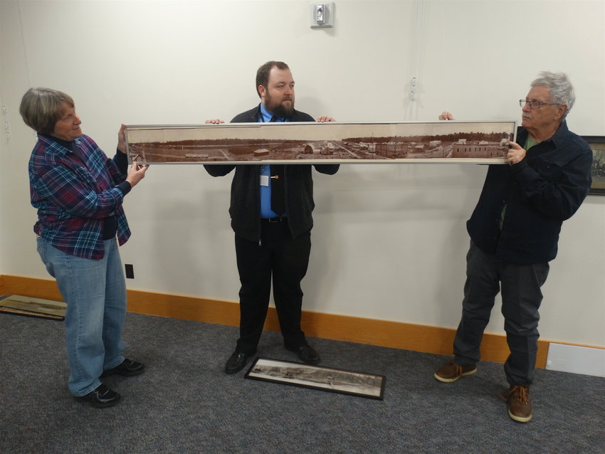 &ldquo;By the Yard: Michigan in Panoramic Photographs&rdquo; organizers Karla Barber, Jacob McCormick and Bill Castanier wrangle a 1901 photo of Johannesburg, a lumber town east of Grayling. The photo was found rolled up in the back of a box at the Archives of Michigan.