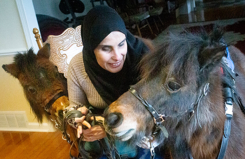 Mona Ramouni with her two mini guide horses, Cherry (left) and Cali, in her home in Okemos.