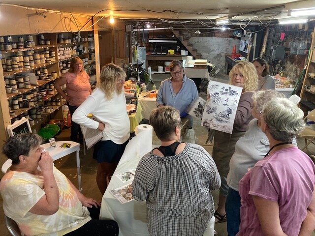 Vendors listen intently as Marilyn Greene of Gallery Eleven 11 LLC explains how to use Dixie Belle&rsquo;s rub-on transfers, in the basement of the Maple Street Mall on May 30.