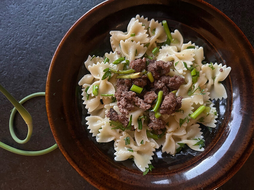 Scape pasta with parsley and a ground beef garnish.