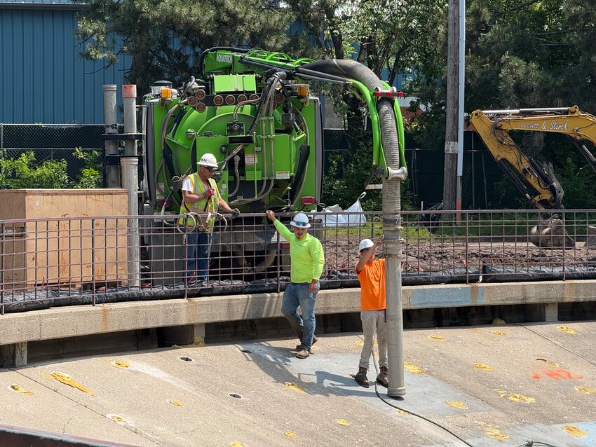 Construction workers from Lansing's Wieland Corp. inject structural foam under Burchard Park's "fishbowl," which was previously floating above empty space. The fishbowl is being renovated to include amphitheater-style seating. About 22,000 pounds of foam and 11 feet of empty space have been filled.