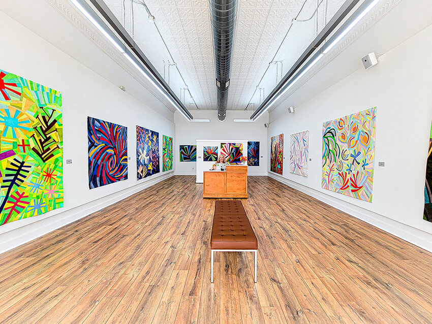 Pamela Loewen works on her laptop in her new Williamston gallery. The gallery focuses primarily on artistic quiltmaking, with its first exhibit showcasing Loewen&rsquo;s own art.