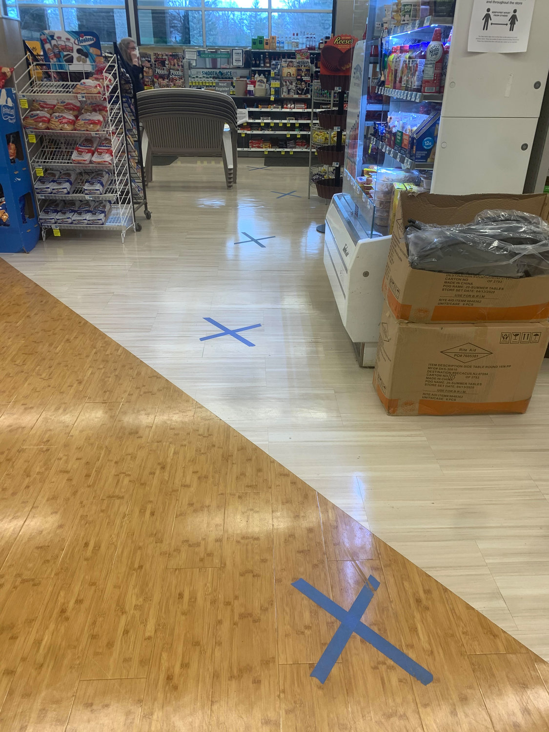 X's taped to the floor instruct customers to keep their distance while waiting in line at Rite Aid.