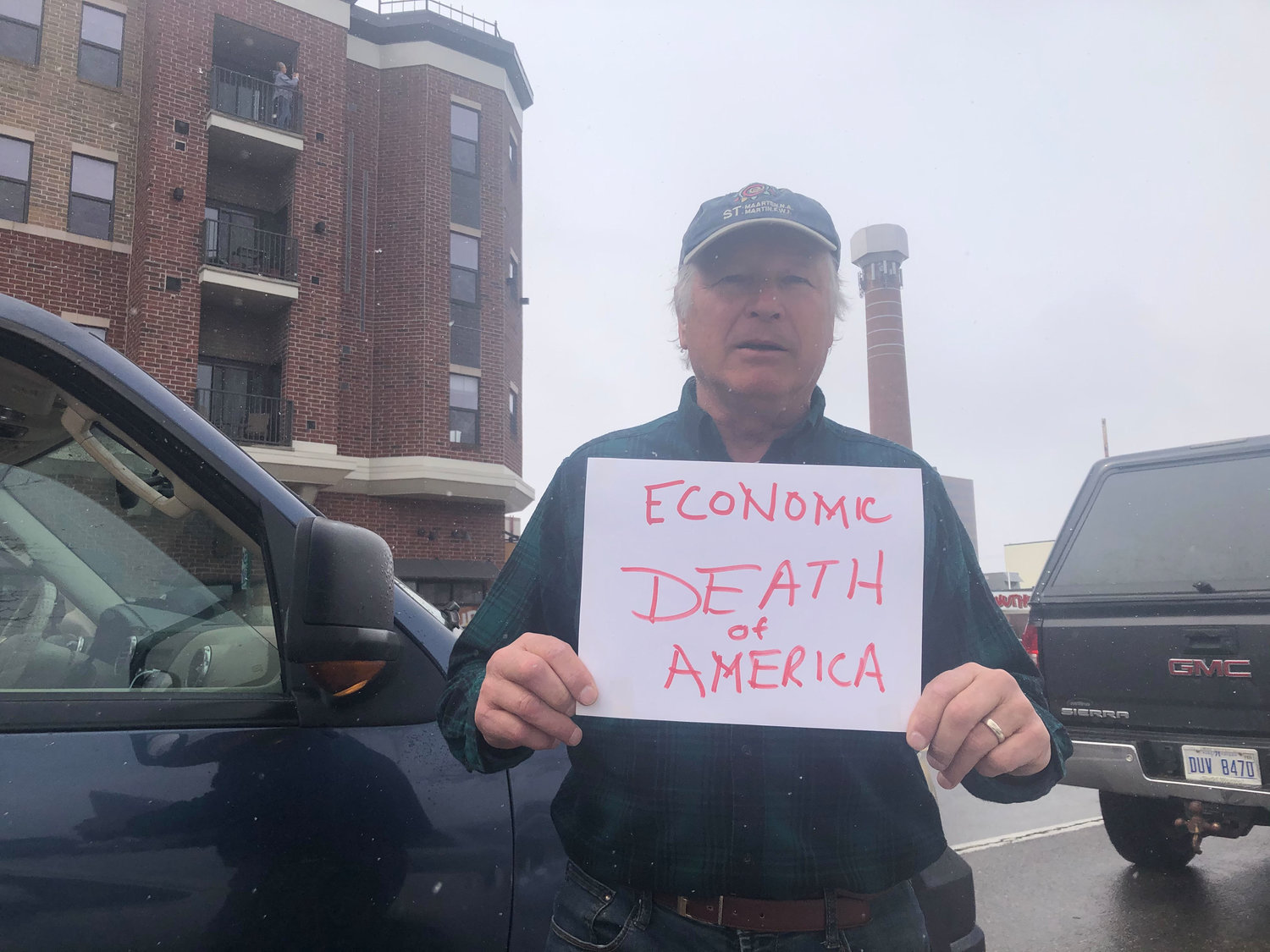 A man at today's protest with a sign reading "Economic Death of America."