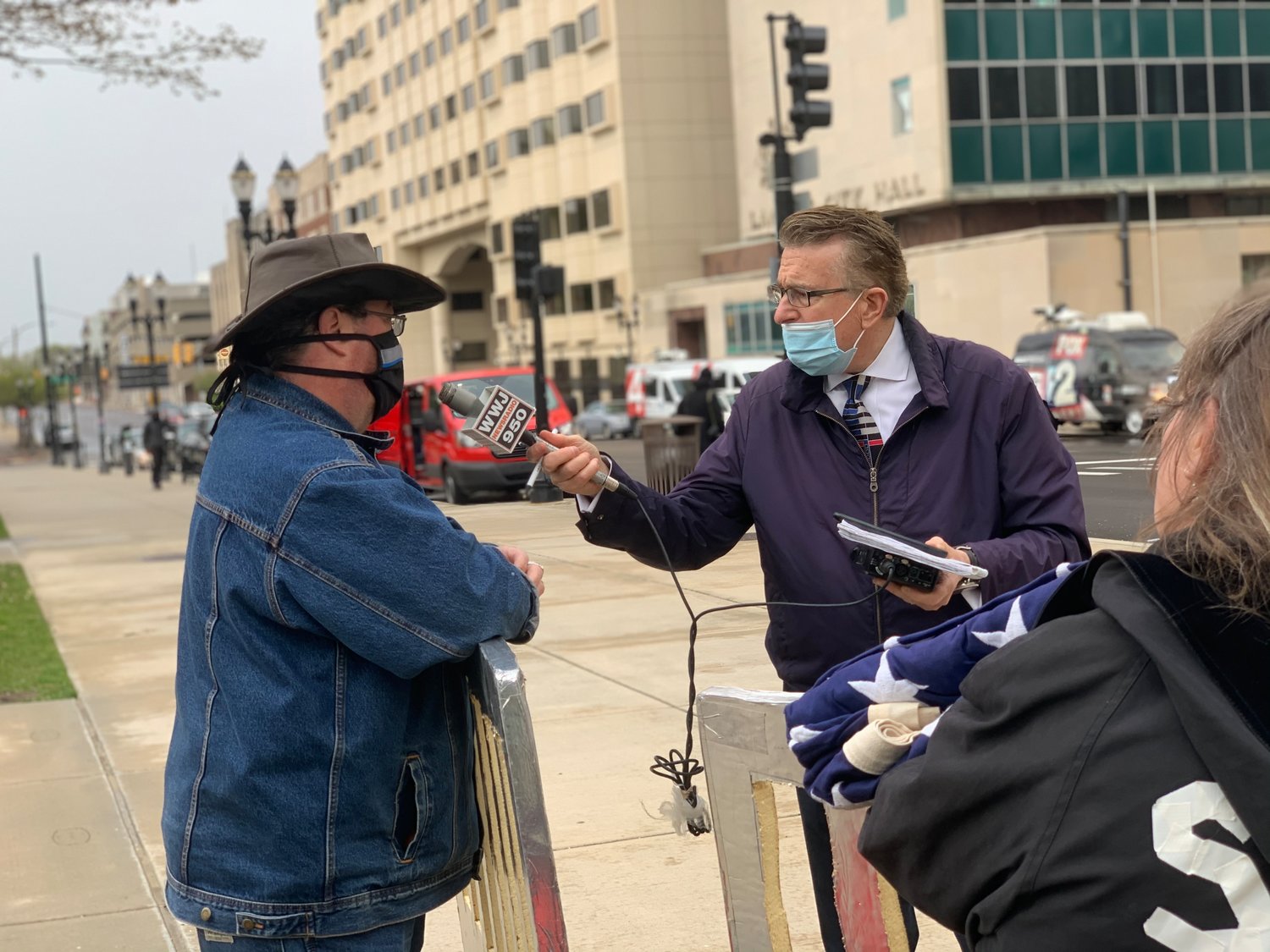 A WWJ Newsradio 950 reporter conducts an interview with his mask below his nose.