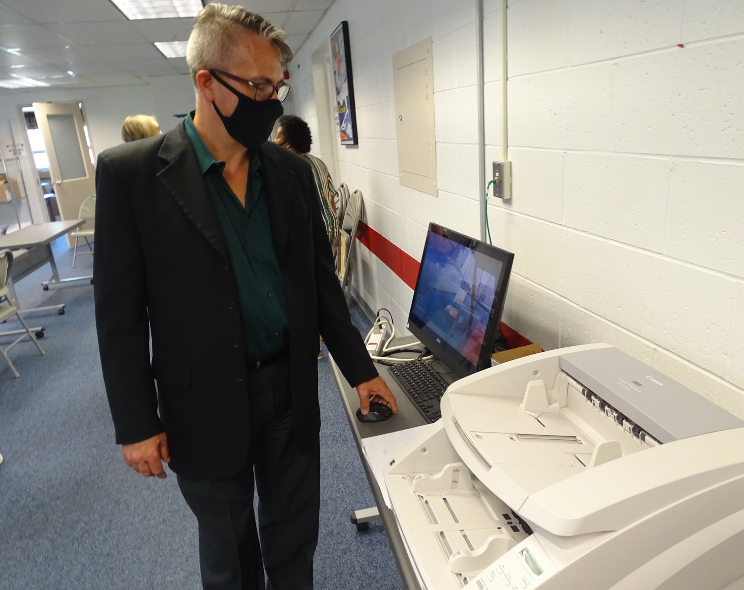 Lansing City Clerk Chris Swope communes with a scanner he’ll use on Election Day to process absentee ballots.