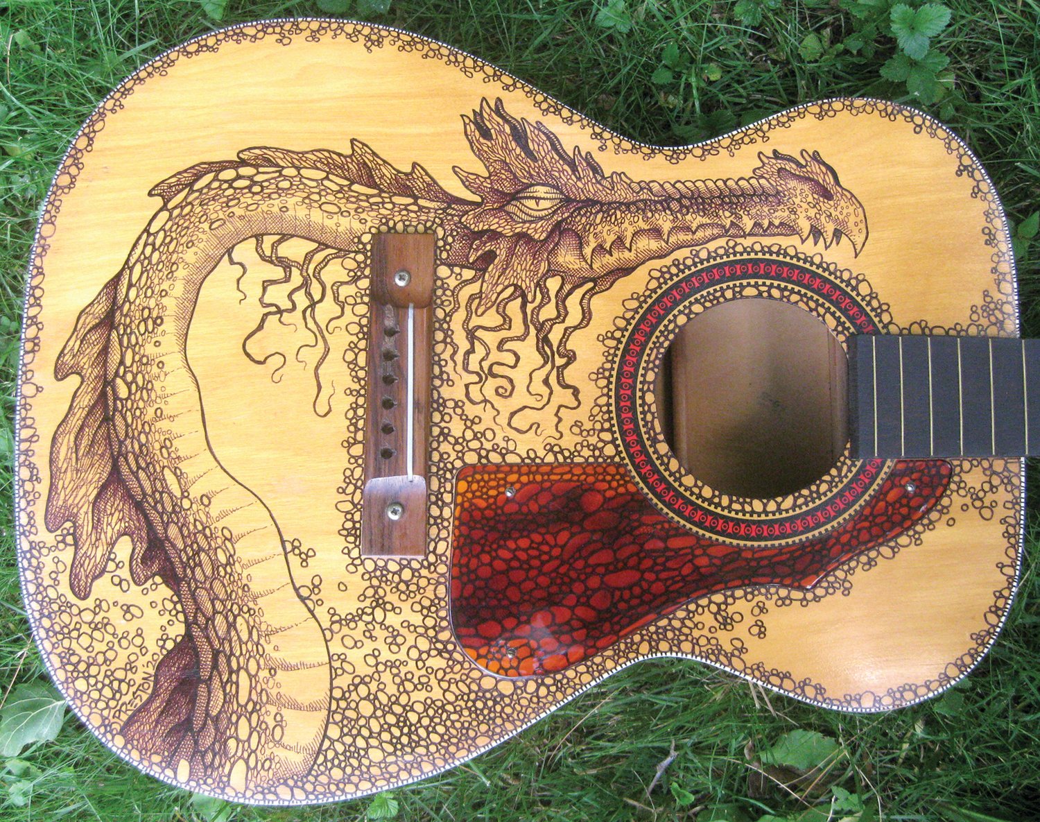 A guitar adorned with an original dragon painting by Dennis Preston.