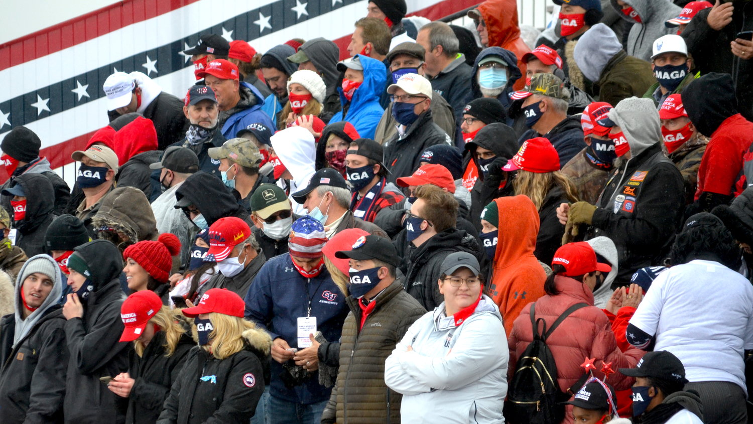 Attendees wait in cold, rainy weather for the start of the Make America Great Again Victory Rally at Capitol Region International Airport.