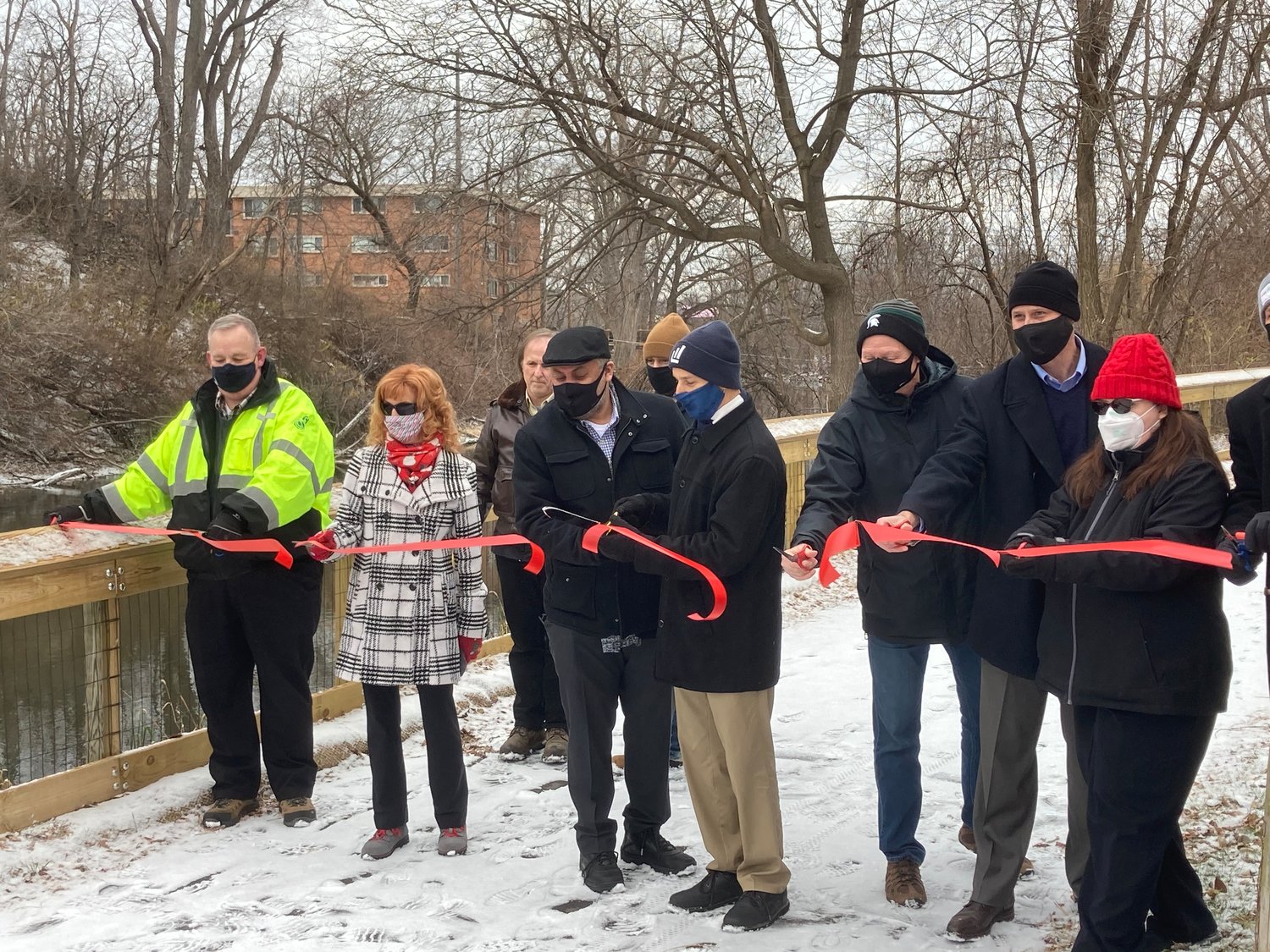 Lansing Mayor Andy Schor cuts a ribbon on the Lansing River Trail on Thursday to commemorate repairs made in 2020. He was joined by several local parks officials, including Ingham County Board of Commissioners Chairman Bryan Crenshaw.