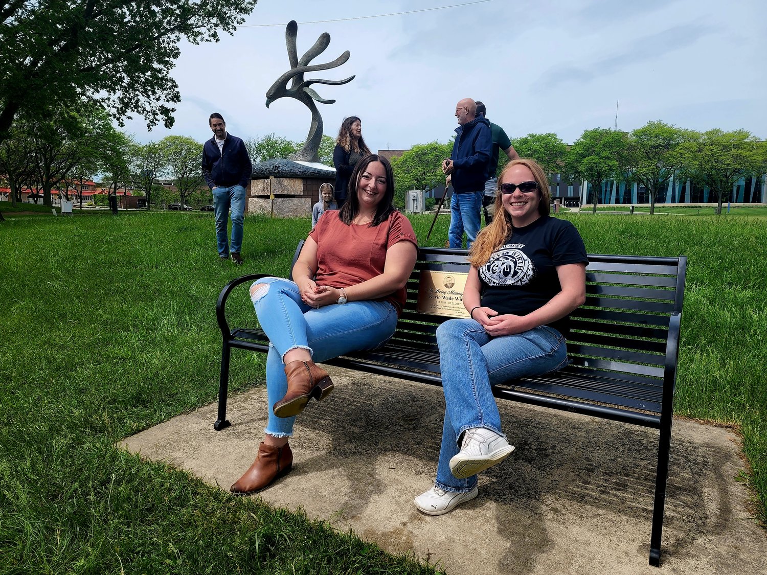 Christin Johnson and Michelle Paye sit on the bench they helped secure for the plaque remembering their murdered friend, Kevin Wirth.