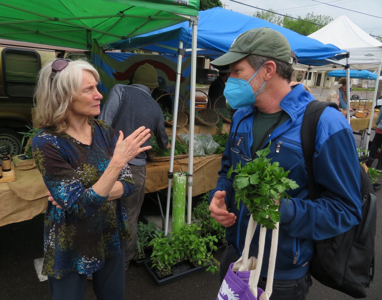 Joan Nelson huddled with East Lansing Food Co-op President Stephen Gasteyer at Wednesday's Allen Farmers Market to plan ELFCO's imminent move into Allen Place this summer.