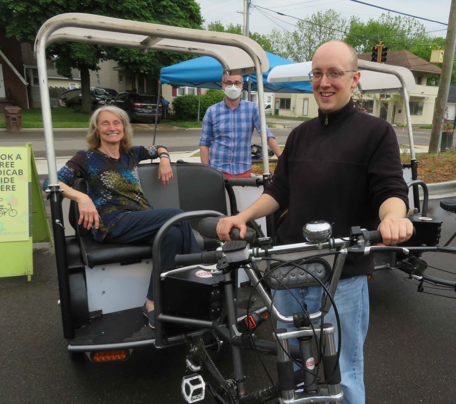 Joan Nelson tries out a pedicab at Wednesday's Allen Farmers Market Wednesday with drivers Zach Whaley (center), David McCarthy (right) and Haley Alderman (not pictured). Free pedicab rides from nearby east side parking lots are the latest innovation at the Allen Farmers Market, the first farmers market in the state to accept EBT cards and food stamps.
