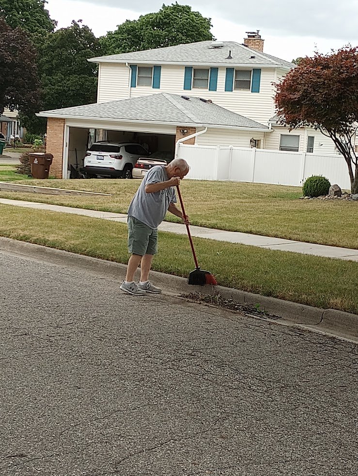 Dave Thompson sweeps in front of his home in Lansing Township. Citing higher taxes he’d have to pay, he opposes being annexed by the city of Lansing. 