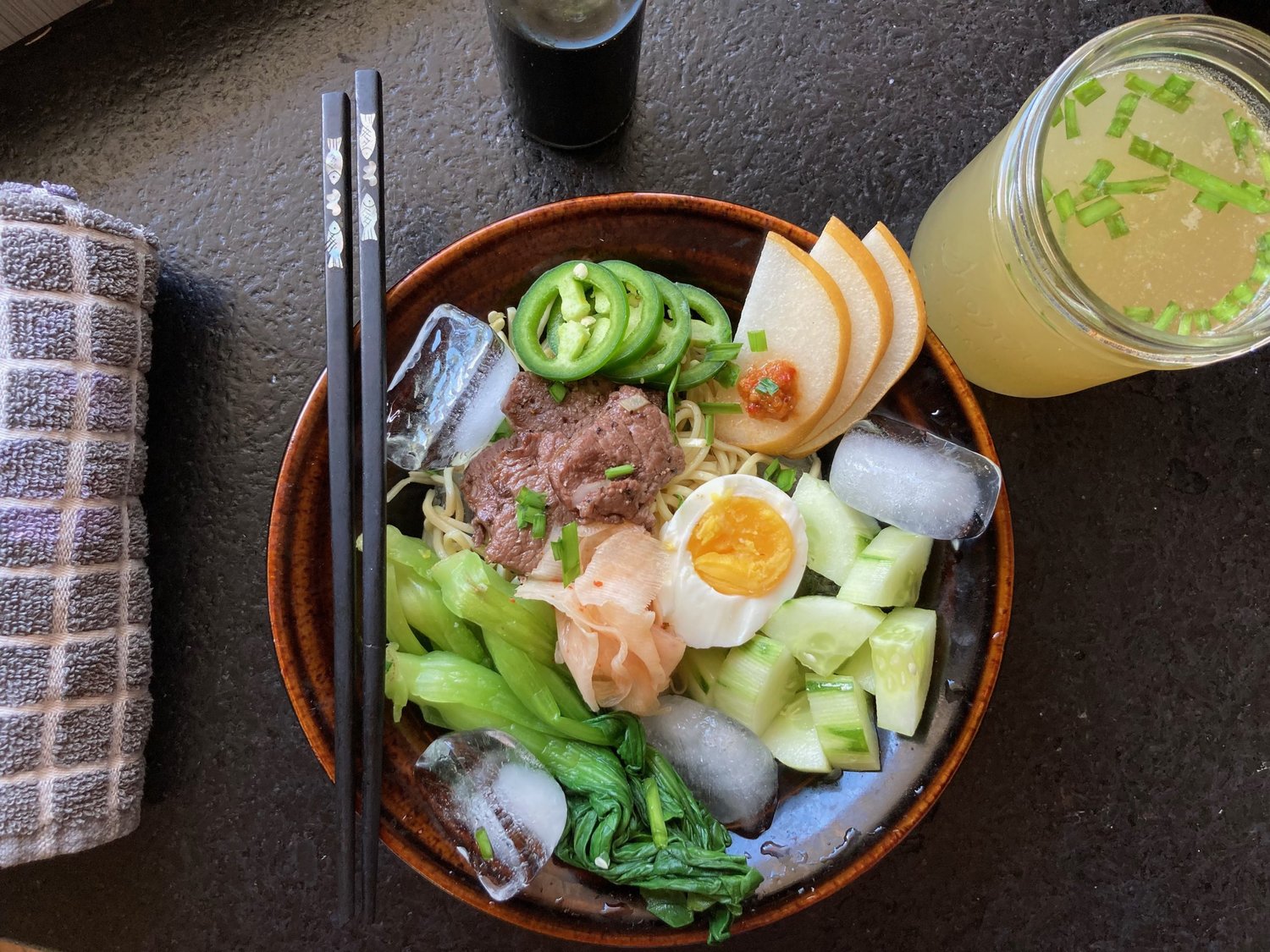 Above, a bowl of naengmyeon, with chilled broth at the ready