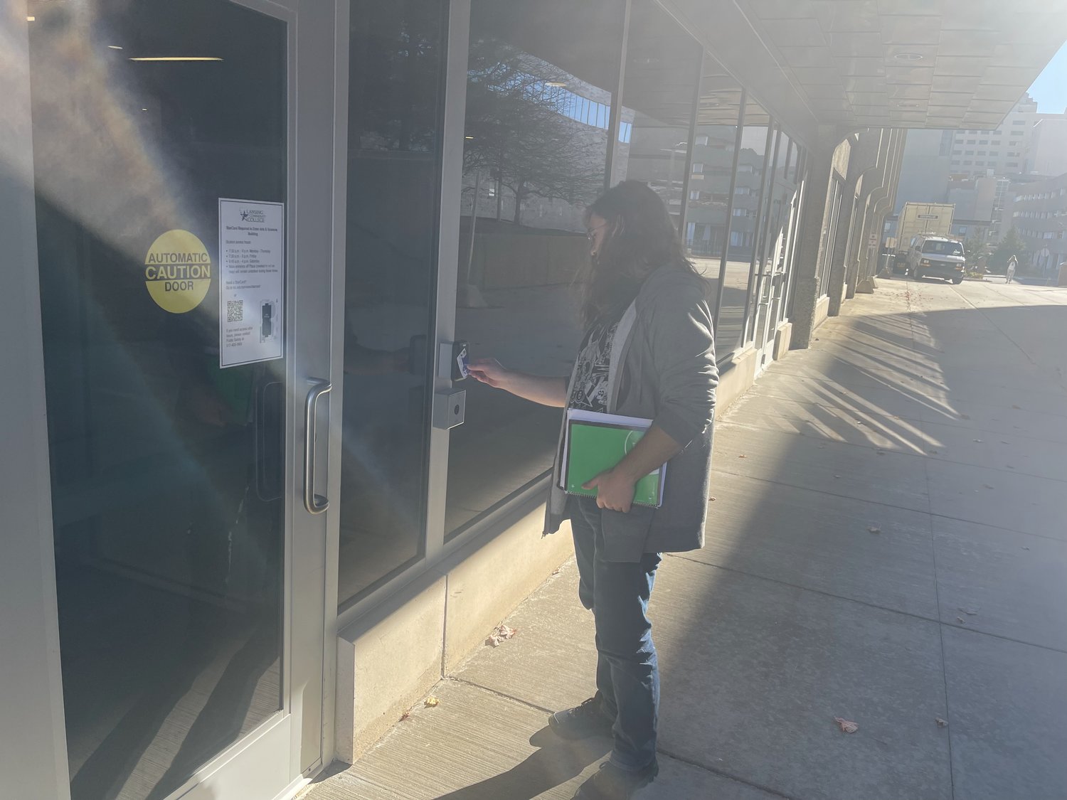 Lansing Community College student Tiernan Henrich uses his ID card to open a door to a building on the downtown campus. LCC is approaching the first anniversary of a new locked-door policy.