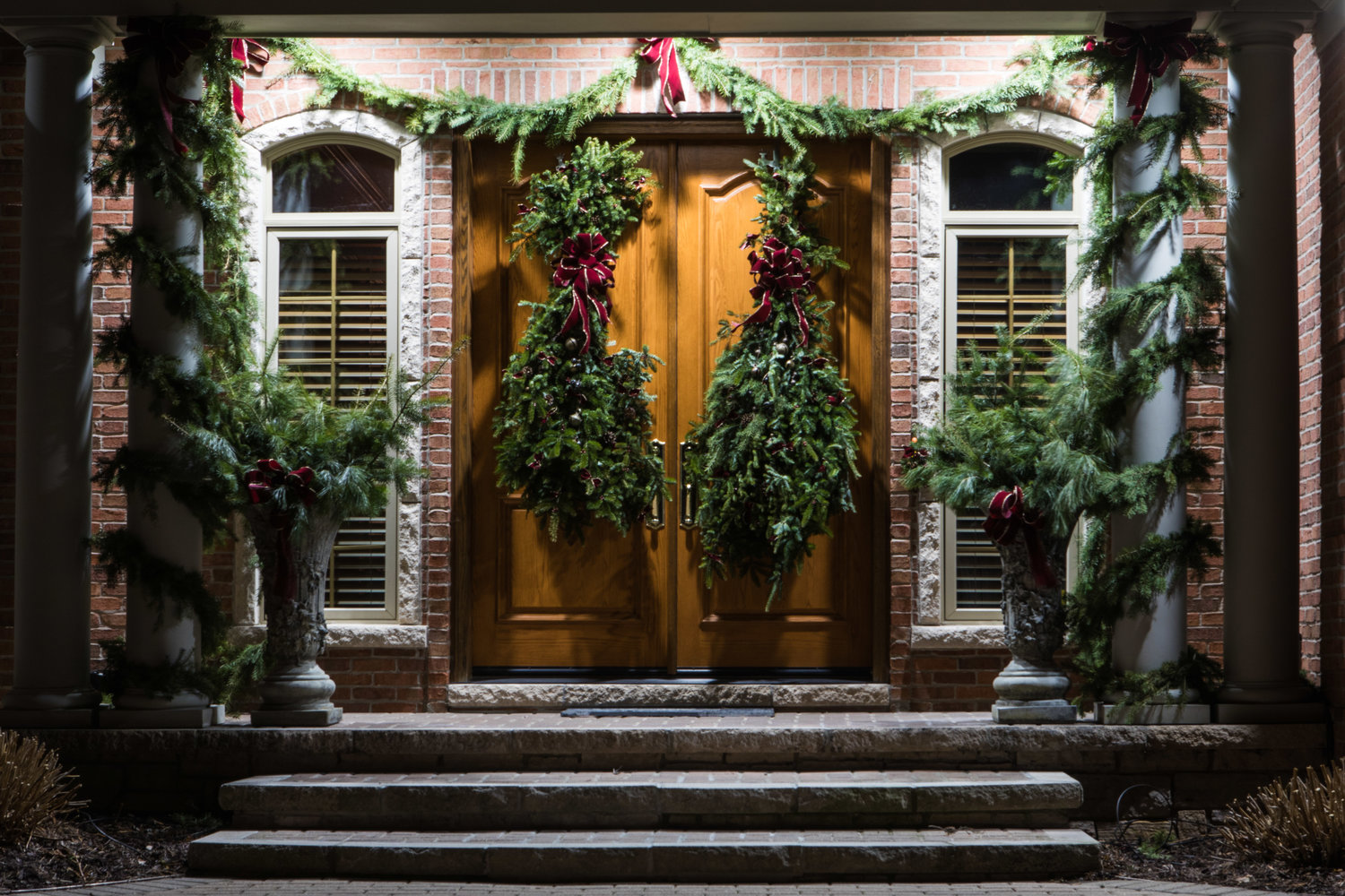 The entrance to this East Lansing home presents an elegant emphasis on garlands, ribbon, and ornaments.