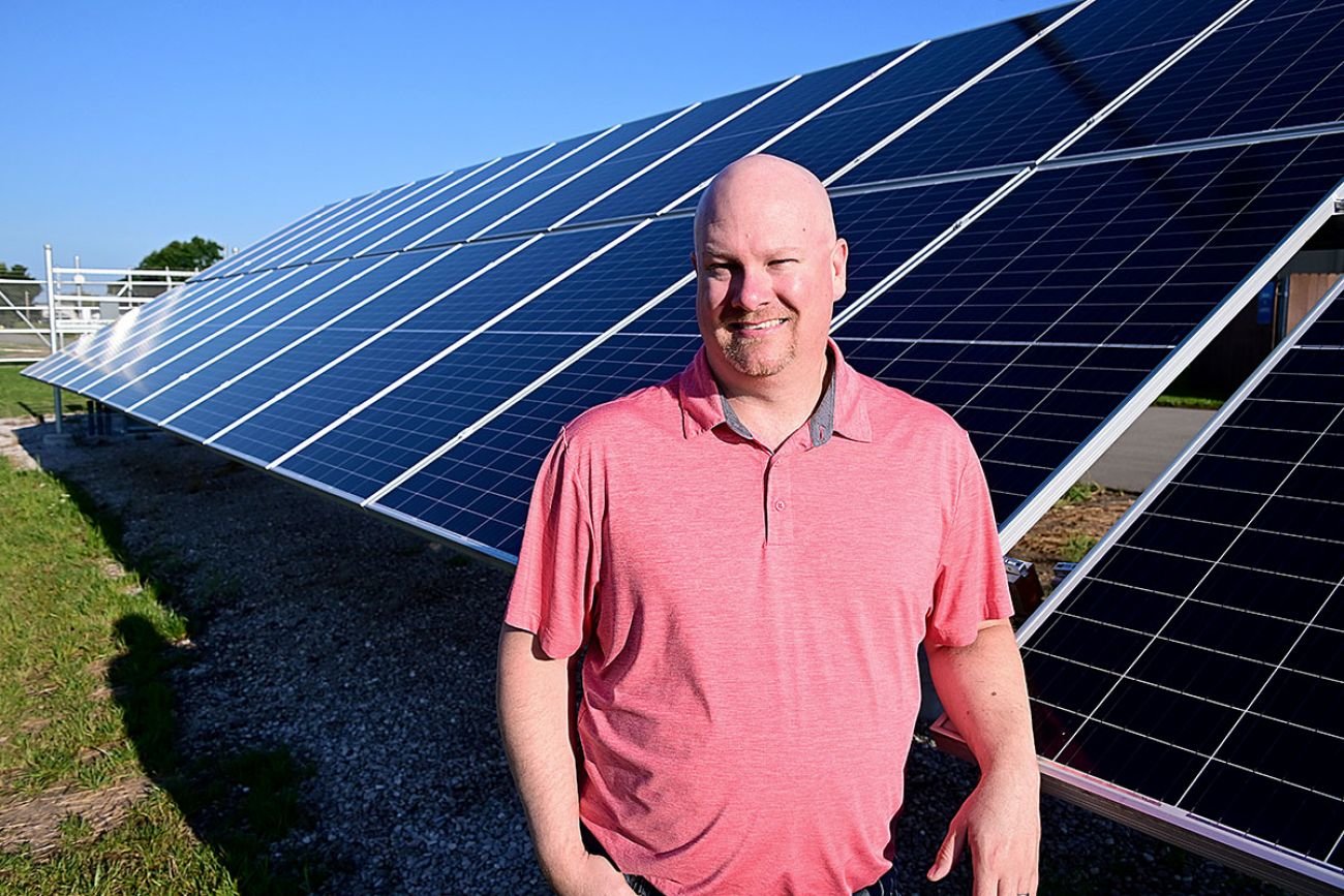 Brian Zatloukal, a senior field leader in renewable energy for Consumers Energy, stands next to a small solar array in Gratiot County. The utility expects to vastly increase its solar energy production in the future.