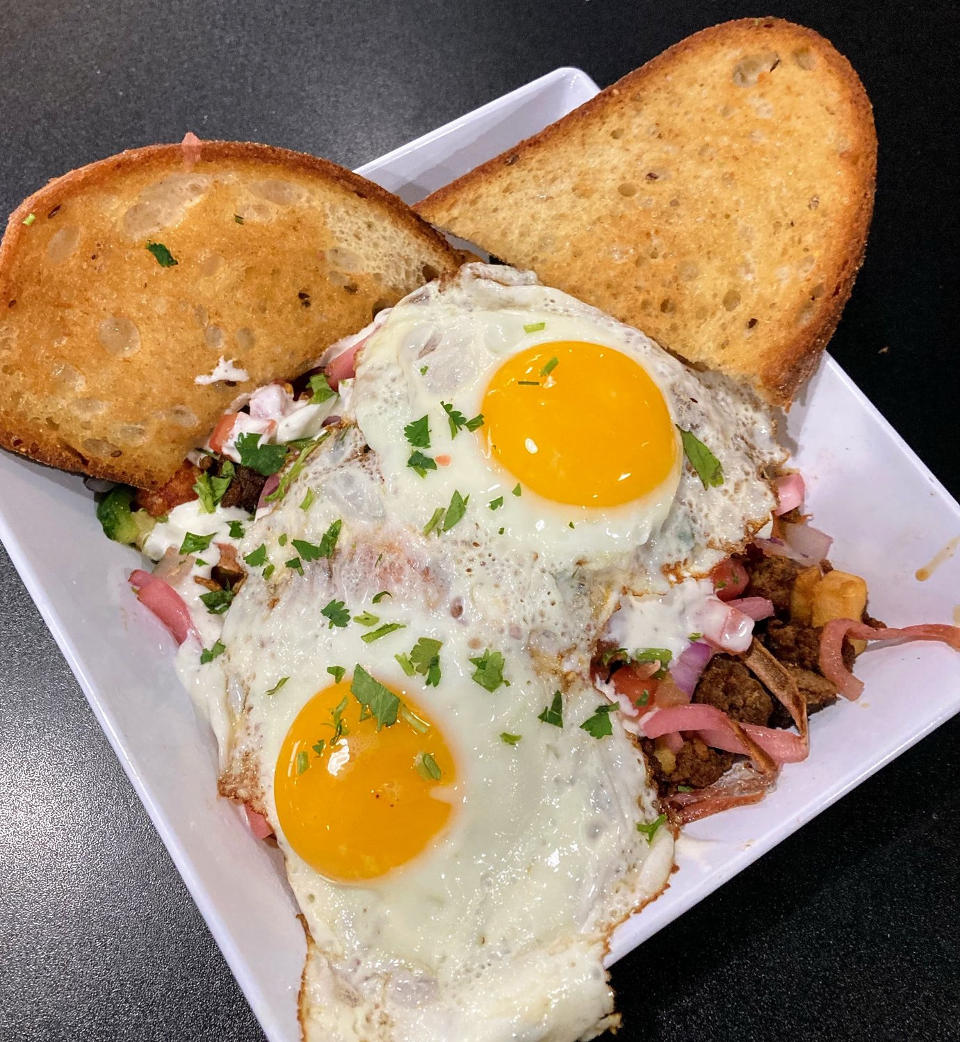 The Cabo Hash at Art’s Pub is composed of sweet potato tots, fried potatoes, fresh peppers, chorizo, queso fresco, pico de gallo, pickled red onions, lime crema and two perfectly cooked sunny-side-up eggs, plus two pieces of toast to assemble a messy, mouthwatering sandwich.