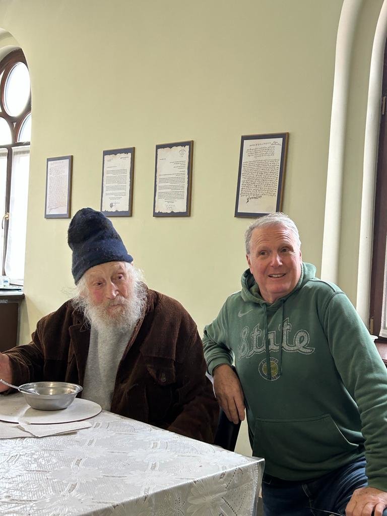 Norkin (right) with an 88-year-old man he identified as Yechiel, whom he said was benefitting from a milk substitute donated by Sparrow Health System. Norkin said Yechiel, who had no family, was living in the attic of a synagogue in Chirnivtsi, Ukaine, near the Romanian border. He said Yechiel was born in Ukraine, then deported “as a Jew” by the Romanian army in 1941 to eastern Russia. He returned after World War II in 1946, but the Communists deported him again, this time to Uzbekistan, “because his family originally had money.” He returned in 1991 and lived alone until his house burned in the war last year.