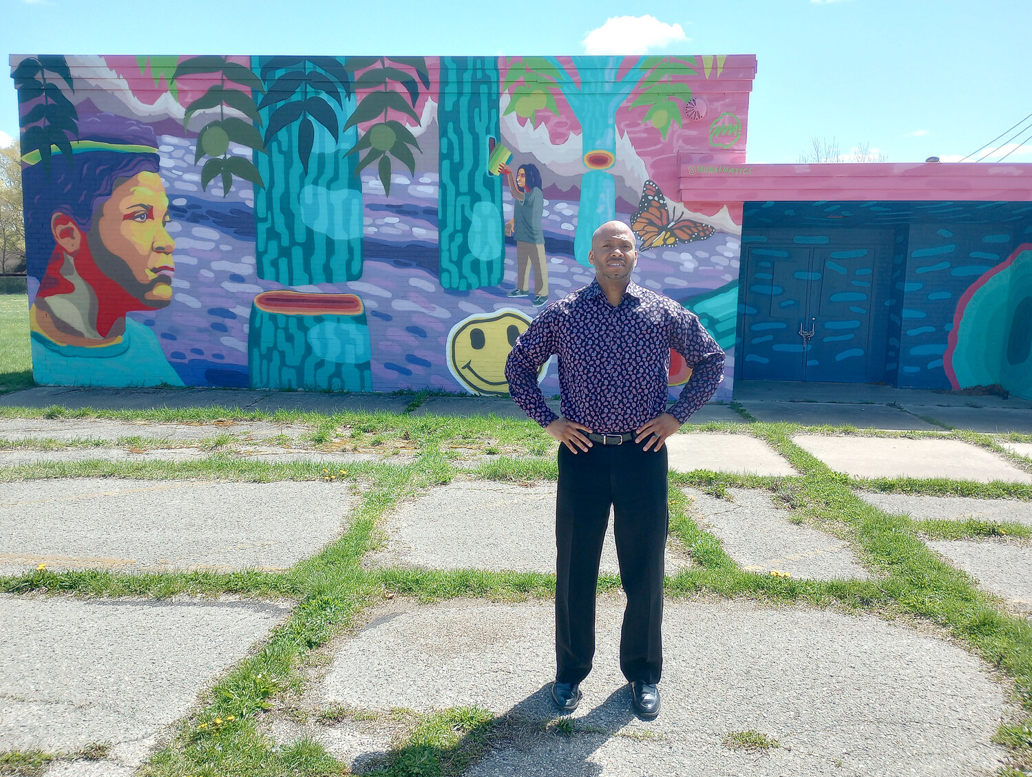 Pastor Coye Bouyer poses in front of a mural that decorates part of the former Maple Grove Elementary School. Bouyer’s congregation at Kingdom Life Church of Lansing bought the school in 2012. It has continued to fall into disrepair and is often the site of sexually explicit images and language.
