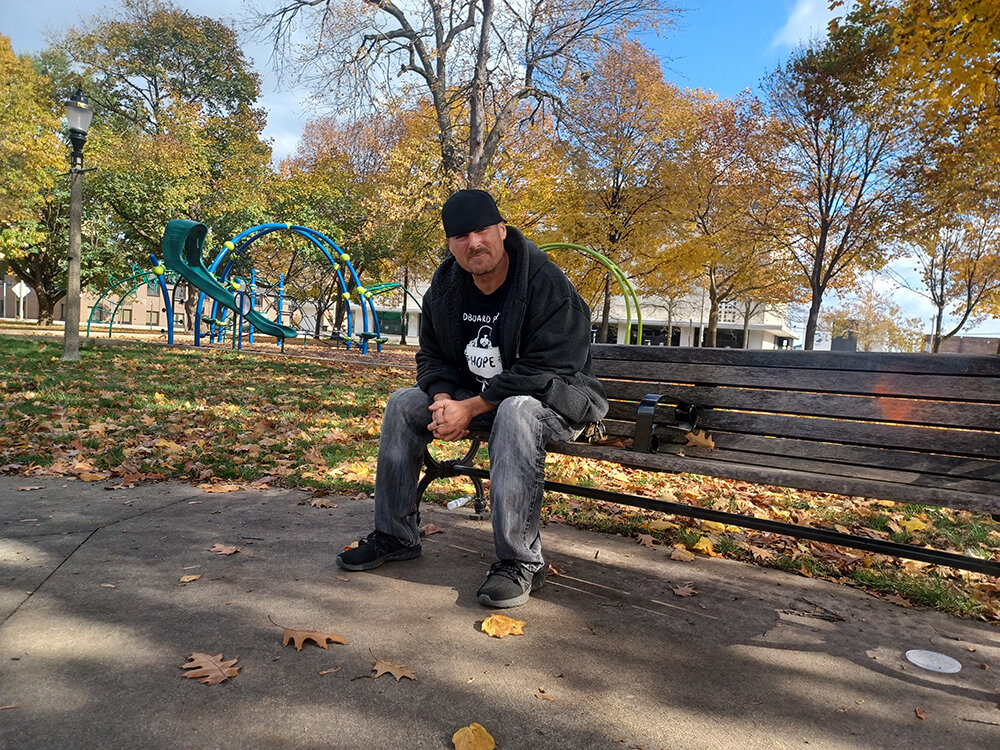 Mike Karl on the bench in Reutter Park in downtown Lansing that he said was his bed when he was homeless. State Rep. Emily Dievendorf cites Karl as her inspiration for her proposed Homeless Bill of Rights.