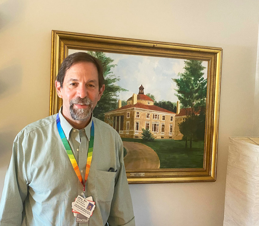 Dr. Jeffrey Borkan, outgoing chair of the Family Medicine Department at the Alpert Medical School at Brown, in his office, standing in front of a painting of the original building at Memorial Hospital.