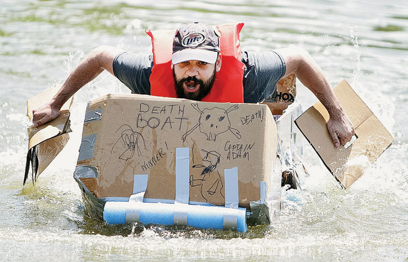 Adam Strunk lunges forward in The Death Boat during the Cardboard Regatta, a community event sponsored by Harvey County Now. He still holds the unofficial course record. (Photo by Wendy Nugent).