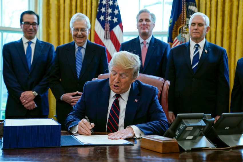President Donald Trump signs the coronavirus stimulus relief package in the Oval Office at the White House, Friday, March 27, 2020, in Washington, as Treasury Secretary Steven Mnuchin, Senate Majority Leader Mitch McConnell, R-Ky., House Minority Leader Kevin McCarty, R-Calif., and Vice President Mike Pence watch. (AP Photo/Evan Vucci)