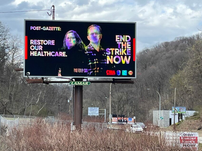 Two striking Pittsburgh news workers &mdash; Kitsy Higgins, left, and Jordan Pass &mdash; are featured on a rotating electronic billboard on Banksville Road, one of a half dozen locations around Pittsburgh to feature the message. (Bob Batz Jr./Pittsburgh Union Progress)