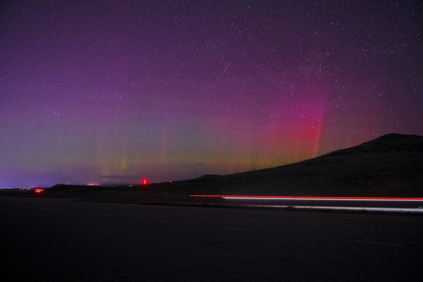 A motorist north on Interstate 90 passes the Scenic Overlook south of Sheridan, Wyo., and provides an interesting foreground in this time exposure of the Aurora Borealis Saturday, May 11, 2024.
