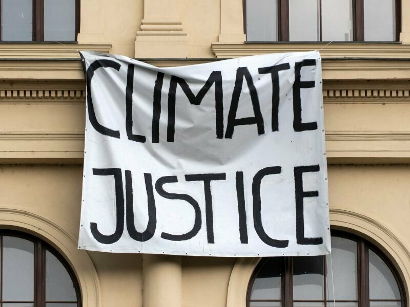 (Photo: Climate justice banner hangs across building. Credit: Canva Pro Stock.)