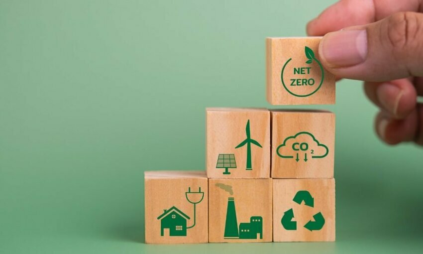 Building blocks with symbols/images related to sustainability and clean energy, being built towards a goal of a net-zero society block.