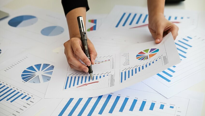 A pair of hands hold a number of papers with data-driven solutions printed on them.