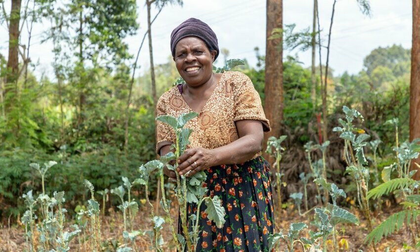 A woman smiling while holding growing plants.