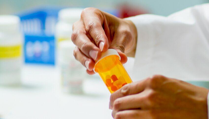 Hands screw on the lid of a prescription bottle